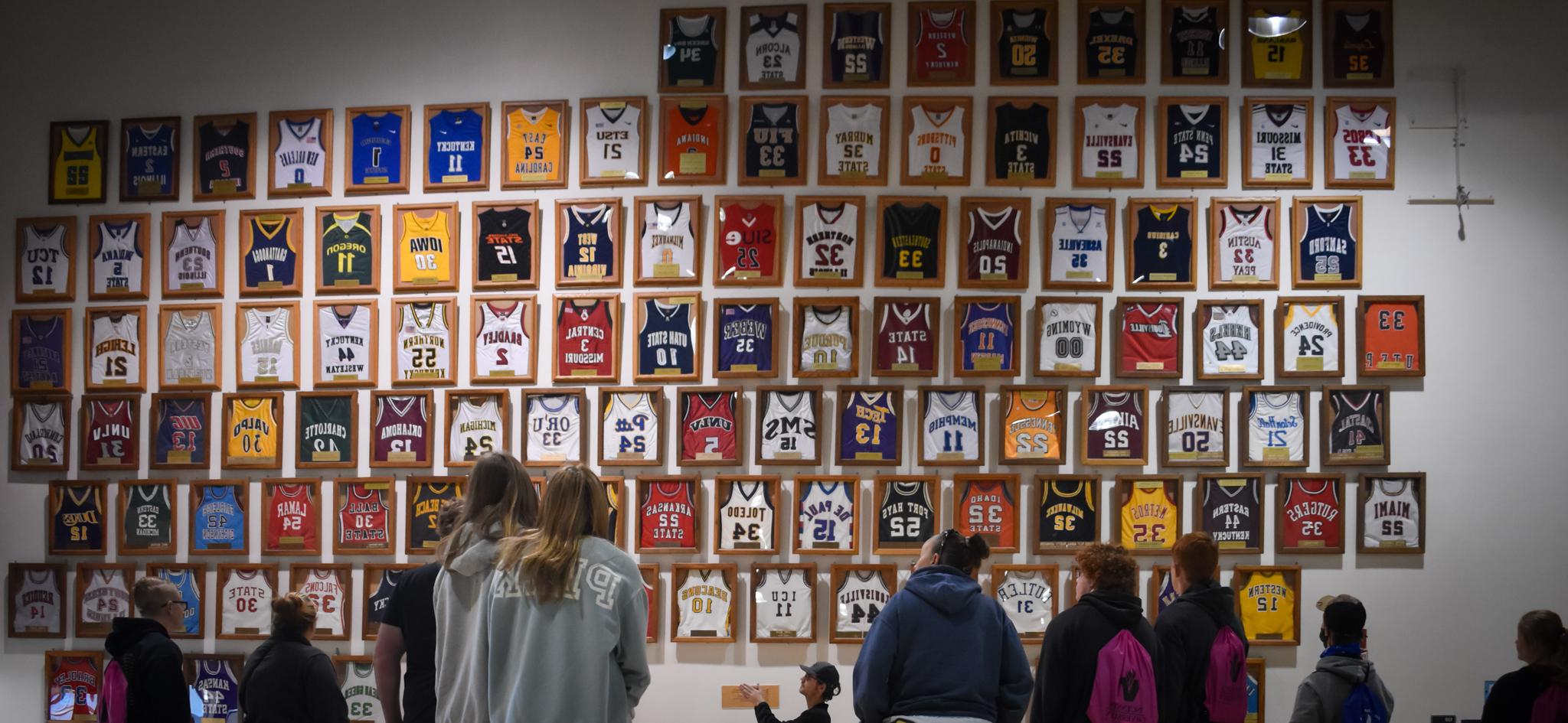 A large number of basketball jerseys hanging on a wall